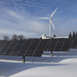 photovoltaik in winterlandschaft mit windkraftwerk